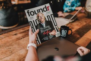 Eine Person hält eine Ausgabe des „foundr“-Magazins mit Richard Branson auf dem Titel in der Hand, während im Hintergrund Menschen an Laptops arbeiten. Die Szene steht sinnbildlich für Unternehmertum und kreative Selbstverwirklichung – eine häufig gewählte berufliche Richtung bei ADHS in der Schweiz.