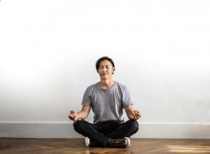 Ein Mann sitzt im Schneidersitz, die Augen geschlossen, in tiefer Konzentration. Die klare, minimalistische Umgebung fördert die innere Ruhe. ADHS Achtsamkeit Schweiz – einfache Übungen für mehr Gelassenheit im Alltag.