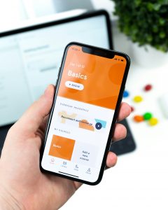 Ein Smartphone zeigt eine geöffnete Achtsamkeits-App mit dem Titel „Basics“ – die Benutzeroberfläche ist klar strukturiert und lädt zur täglichen Nutzung ein. Im Hintergrund ist ein unscharfer Laptop sichtbar, was auf eine digitale Arbeitsumgebung hinweist. In der Behandlung von ADHS Schweiz können solche Apps zur Unterstützung der Selbstregulation und zur Stressreduktion beitragen. 