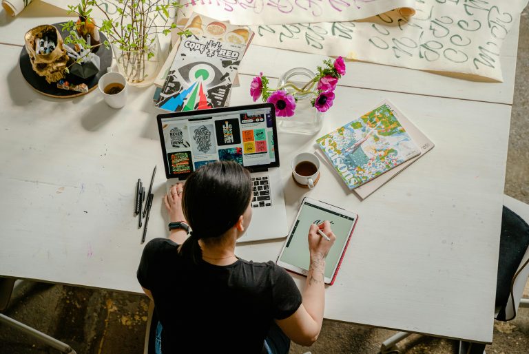 Eine kreative Berufstätige arbeitet gleichzeitig am Laptop und Tablet, um Designideen umzusetzen. Diese visuelle Darstellung zeigt, wie Menschen mit ADHS im Beruf in der Schweiz kreative Tätigkeiten strukturieren und effektiv nutzen können.
