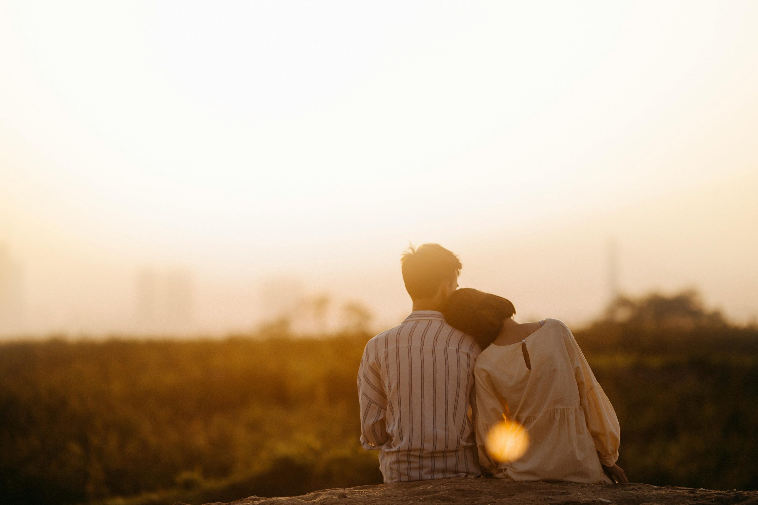 Ein Paar sitzt eng beieinander und blickt gemeinsam in den Sonnenuntergang. Für Menschen mit ADHS im Beruf in der Schweiz kann eine stabile Partnerschaft ein wichtiger Anker im Alltag sein.