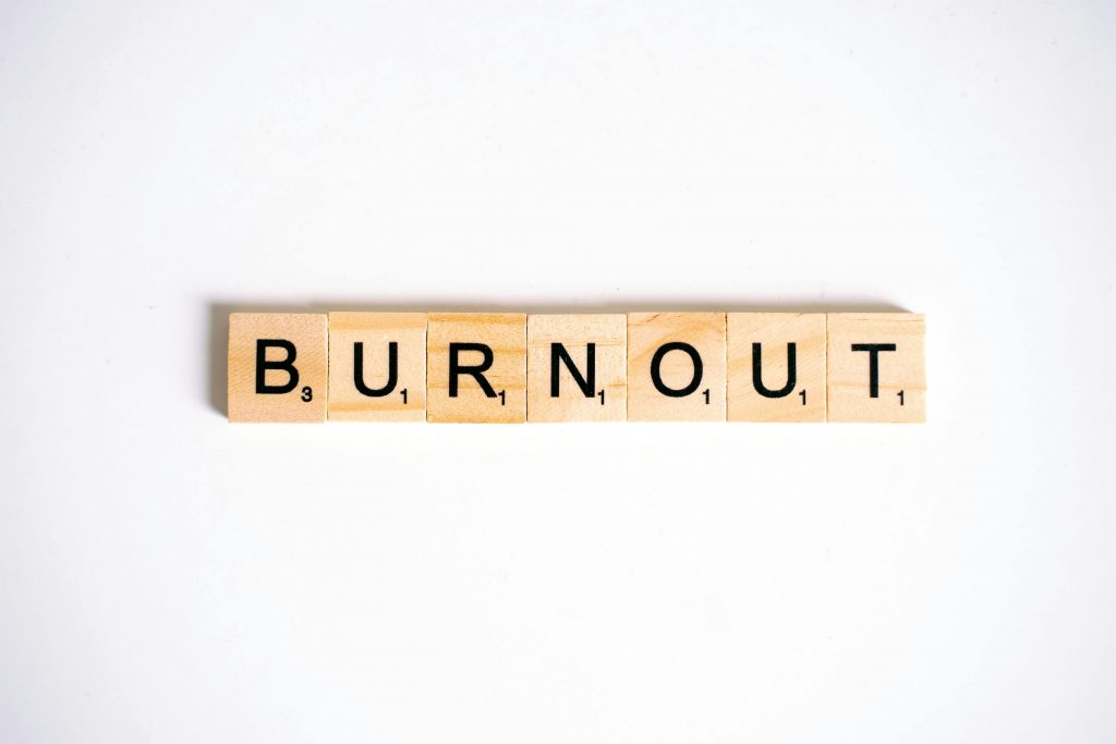 Das Wort „BURNOUT“ ist mit Holzbuchstaben gelegt, minimalistisch auf weissem Hintergrund. ADHS Schweiz thematisiert häufig den Zusammenhang zwischen Reizüberflutung, Stress und Burnout. Die Darstellung unterstreicht die Wichtigkeit, Burnout frühzeitig zu erkennen und zu handeln.