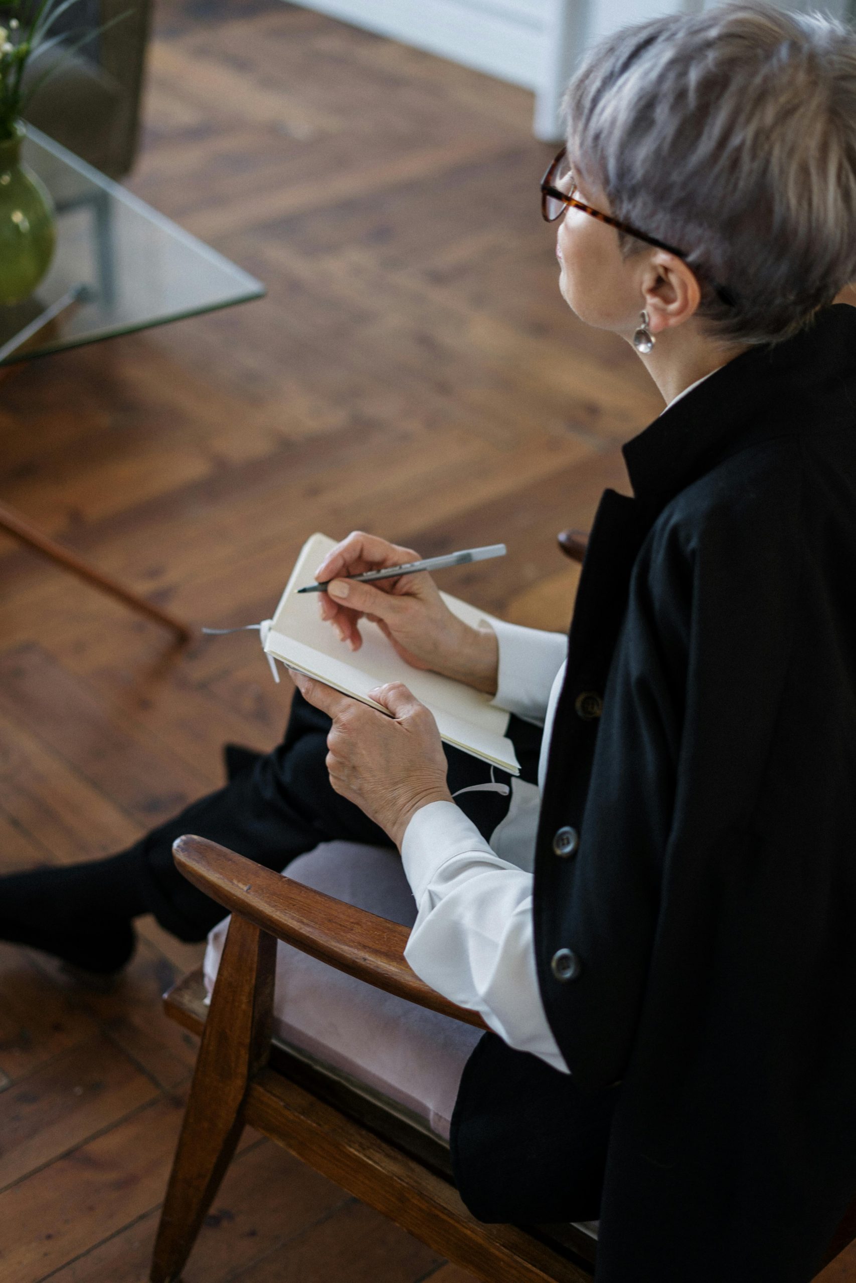 Eine ältere Frau mit Kurzhaarschnitt und Brille macht sich konzentriert Notizen während eines Gesprächs. Das Bild steht für psychologische Beratung in der Schweiz – ein möglicher erster Schritt für Menschen mit ADHS-Symptomen auf der Suche nach Orientierung.