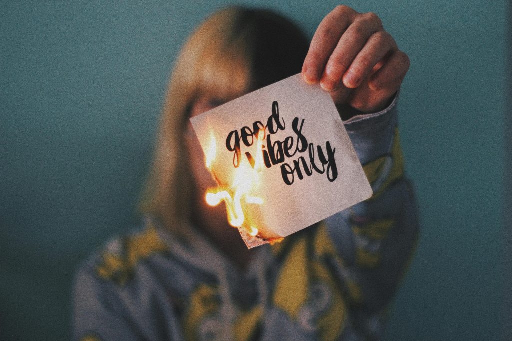 Eine Person hält einen brennenden Zettel mit der Aufschrift „Good Vibes Only“ in die Kamera. Das Bild transportiert das Gefühl von Rebellion gegen toxische Positivität – eine Realität, mit der viele Menschen mit ADHS in der Schweiz konfrontiert sind, wenn ihre Symptome nicht ernst genommen werden.