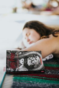 Eine junge Frau schläft auf einem Sofa ein, neben ihr liegt das Buch „Harry Potter and the Sorcerer's Stone“. Die Szene strahlt Erschöpfung und Tagträumerei aus. Müdigkeit und Konzentrationsprobleme sind häufige Begleiterscheinungen bei ADHS Schweiz.