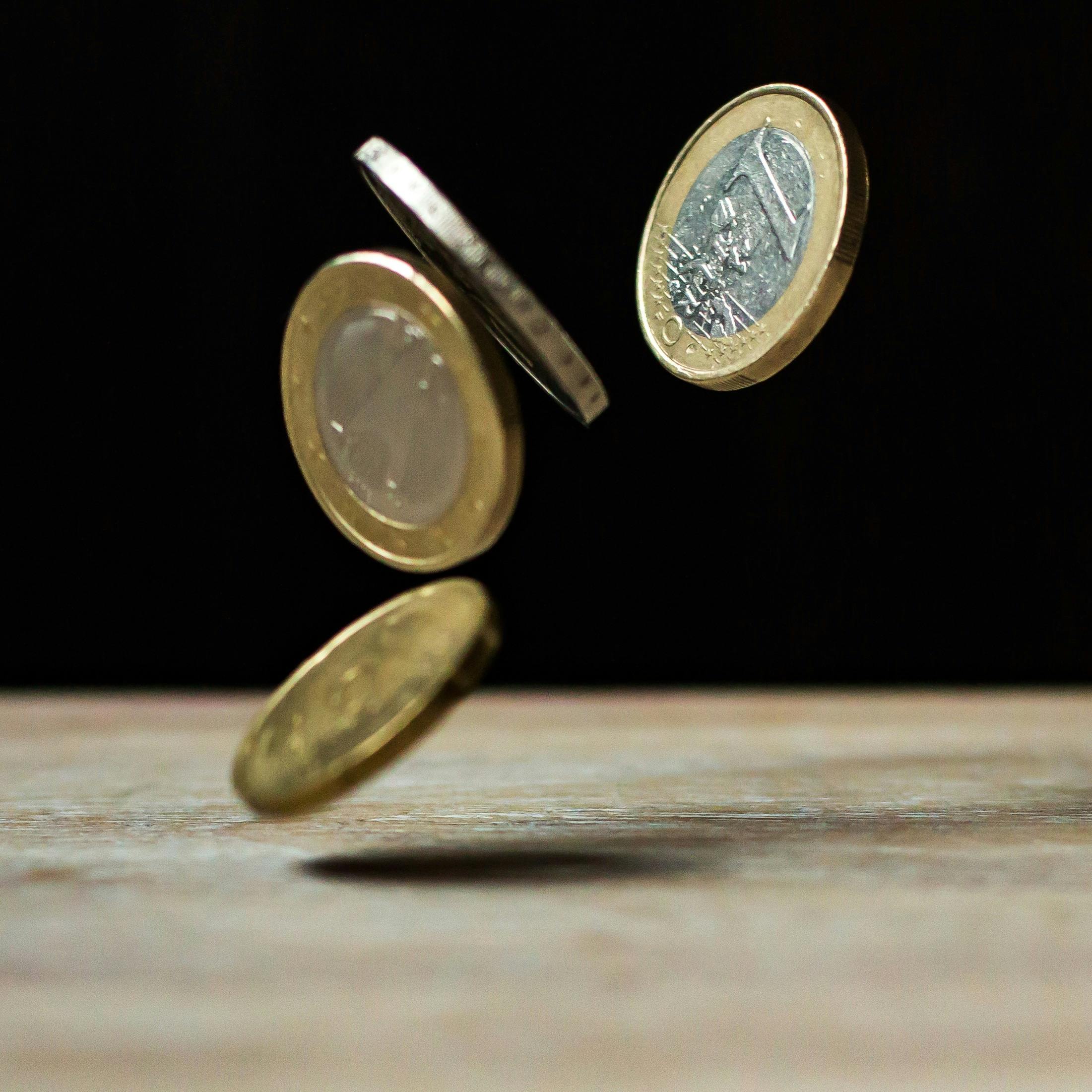 Mehrere Euromünzen fallen in der Bewegung und symbolisieren einen unkontrollierten Geldfluss. Bei ADHS kann der Umgang mit Geld schnell zur Reizüberflutung führen – auch in der Schweiz, wo viele alltägliche Ausgaben digitale Aufmerksamkeit verlangen.