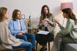 Mehrere junge Erwachsene sitzen gemeinsam mit einer Therapeutin im Gesprächskreis. Die Atmosphäre ist ruhig und aufmerksam, alle Teilnehmenden wirken involviert. Die Szene zeigt eine typische ADHS-Gruppentherapie in der Schweiz, bei der Austausch und gegenseitige Unterstützung im Mittelpunkt stehen.