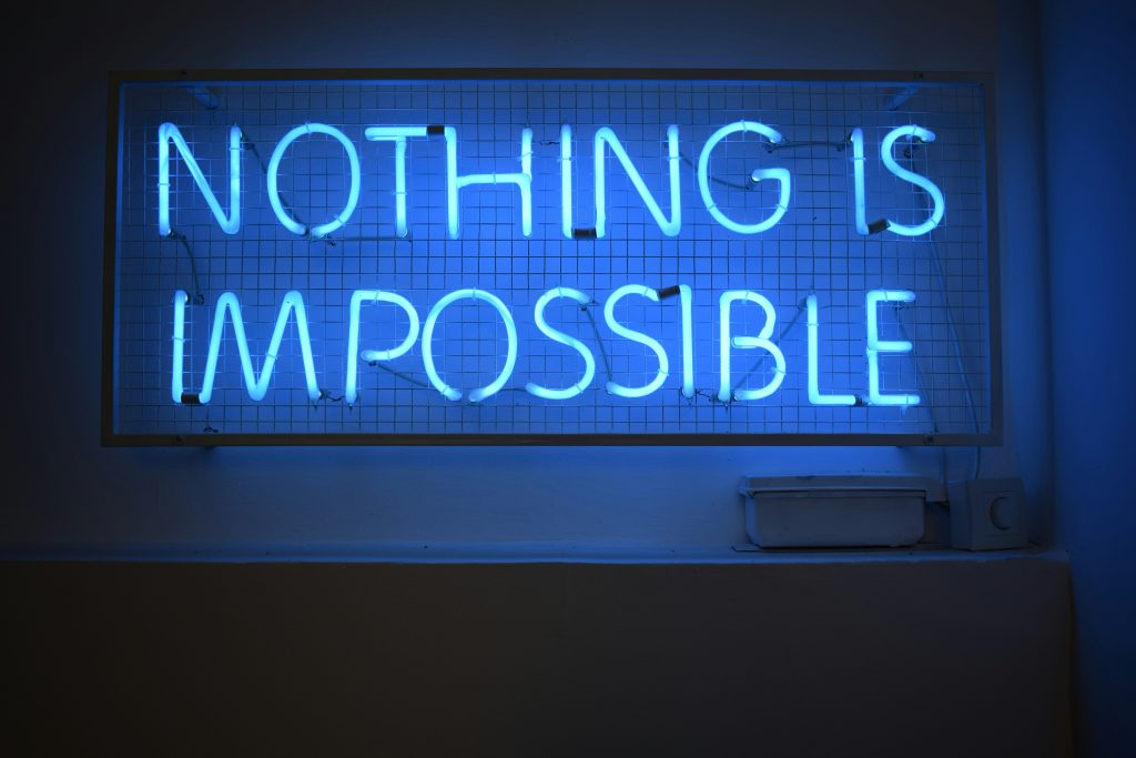 Ein blaues Neonlicht mit der Aufschrift „Nothing is impossible“ leuchtet als kraftvolle Botschaft in einem dunklen Raum. Diese Aussage kann Menschen mit ADHS in der Schweiz Mut machen, trotz Herausforderungen ihren eigenen Weg zu gehen und Unterstützung anzunehmen.