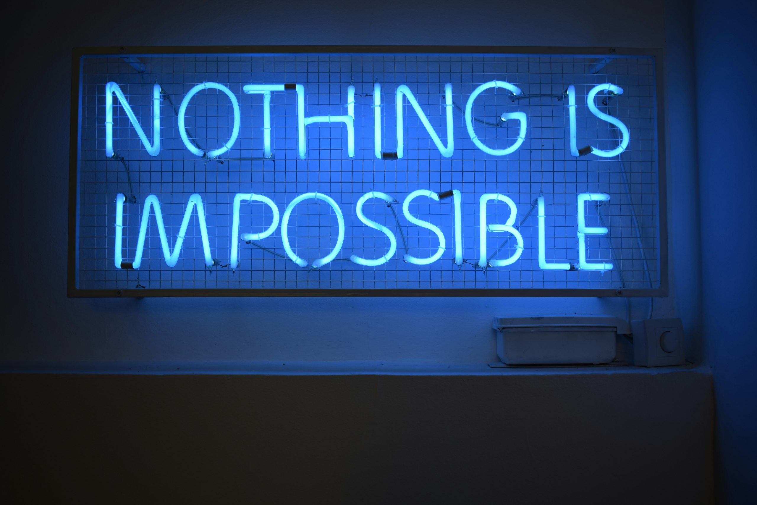 Ein blaues Neonlicht mit der Aufschrift „Nothing is impossible“ leuchtet als kraftvolle Botschaft in einem dunklen Raum. Diese Aussage kann Menschen mit ADHS in der Schweiz Mut machen, trotz Herausforderungen ihren eigenen Weg zu gehen und Unterstützung anzunehmen.