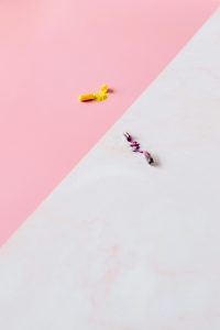 Eine aufgebrochene gelbe Kapsel mit Pulverinhalt liegt auf einem rosa und weißen Hintergrund. Daneben ist eine weitere geöffnete Kapsel mit lila-farbenem Inhalt zu sehen. Nahrungsergänzungsmittel können bei ADHS Schweiz unterstützend eingesetzt werden.