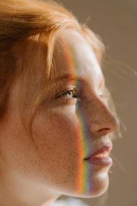 Ein Regenbogenlicht fällt über das Gesicht einer Frau, direkt über das Auge. Dieses Bild steht sinnbildlich für die Vielschichtigkeit von ADHS und Hochsensibilität – bunt, intensiv und oft unsichtbar für andere.