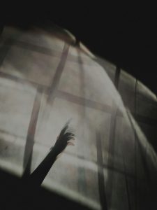 Eine verschwommene Hand streckt sich durch eine durchscheinende Stoffwand. Das Bild symbolisiert Unsicherheit, Reizüberflutung und das Gefühl, nicht ganz durchzudringen – typische Empfindungen bei Hochsensibilität und ADHS.