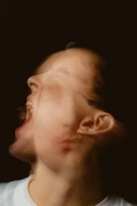 Das Bild zeigt ein verzerrtes, mehrfach belichtetes Gesicht – Ausdruck innerer Unruhe, Überforderung oder emotionaler Dysregulation. Genau das erleben viele Menschen mit ADHS bei Reizüberflutung in der Schweiz. Das Bild steht sinnbildlich für das innere Chaos bei starker sensorischer Belastung.
