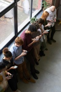 Eine Gruppe junger Menschen steht nebeneinander und blickt konzentriert auf ihre Smartphones. Das Bild zeigt die intensive Nutzung von Mobilgeräten im Alltag. Auch im Zusammenhang mit ADHS Schweiz wird die Smartphone-Nutzung häufig thematisiert.
