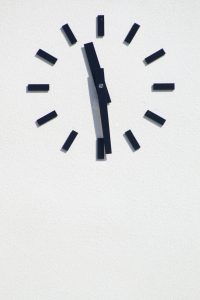 Eine minimalistische Wanduhr zeigt kurz vor zwölf Uhr. Klare Linien und das reduzierte Design symbolisieren Struktur und Zeitbewusstsein – wichtige Themen im Alltag mit ADHS im Beruf in der Schweiz.