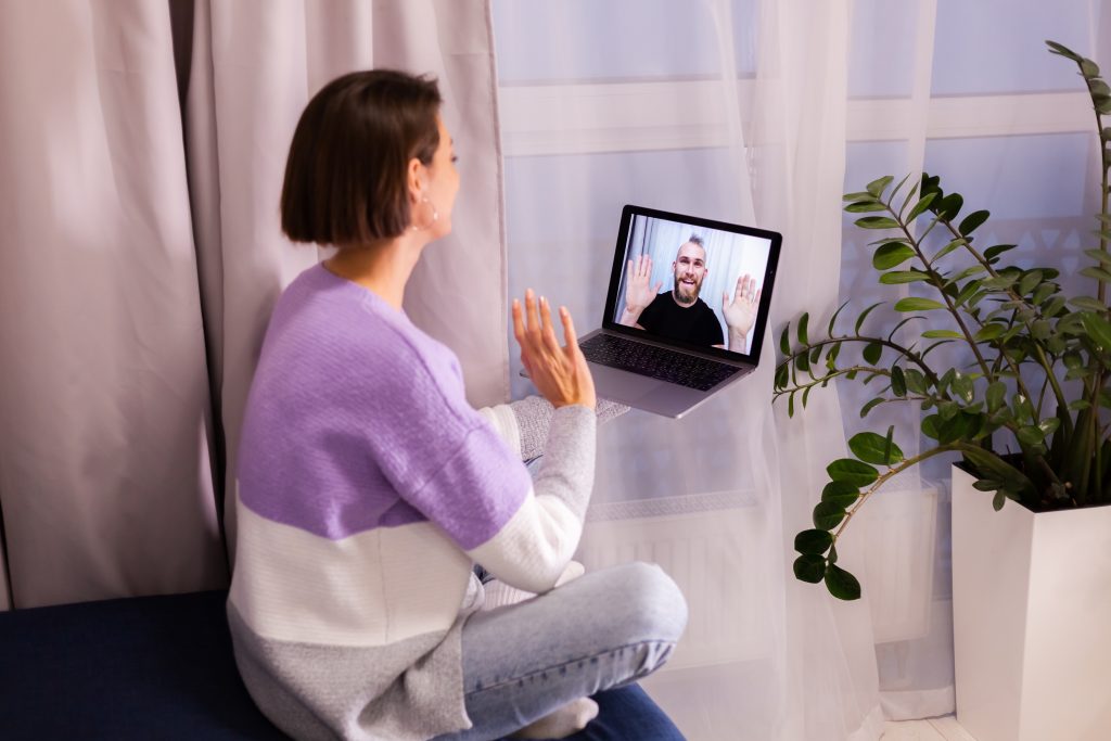 Eine Frau sitzt in gemütlicher Atmosphäre zu Hause und führt einen Videocall mit einem lächelnden Mann auf ihrem Laptop. Digitale Psychotherapie kann auch bei ADHS in der Schweiz eine flexible und wirkungsvolle Unterstützung bieten. Online-Gespräche ermöglichen es Betroffenen, ortsunabhängig professionelle Hilfe zu erhalten.