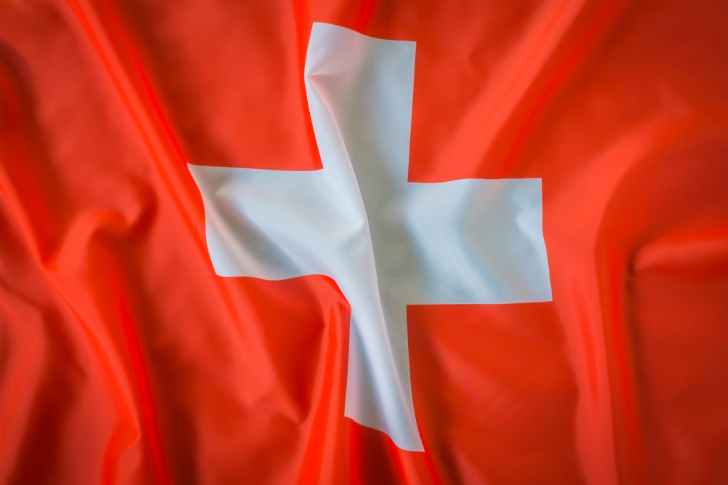 Die Schweizer Flagge mit weissem Kreuz auf rotem Hintergrund ist leicht gefaltet und wirkt lebendig im Licht. Das Symbol steht für Neutralität, Stabilität und das Gesundheitssystem der Schweiz. Gerade für Menschen mit ADHS Schweiz ist der Zugang zu klaren Strukturen und verlässlichen Angeboten ein zentraler Bestandteil der Versorgung.