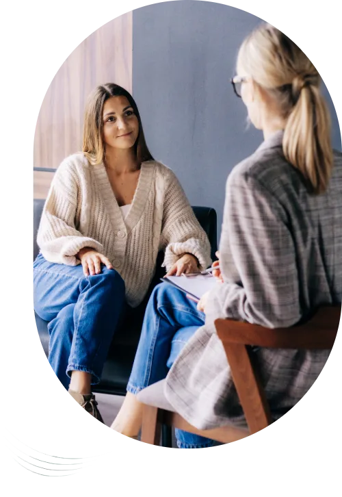 Psychotherapiesitzung bei klaroADHS: Die Patientin sitzt auf einem Sofa, die Therapeutin auf einem Stuhl schräg gegenüber