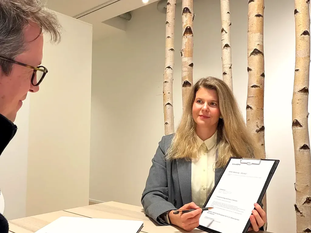 Therapeutin der klaro ADHS Praxis im Gespräch mit einem Patienten, im Hintergrund Birkenstämme